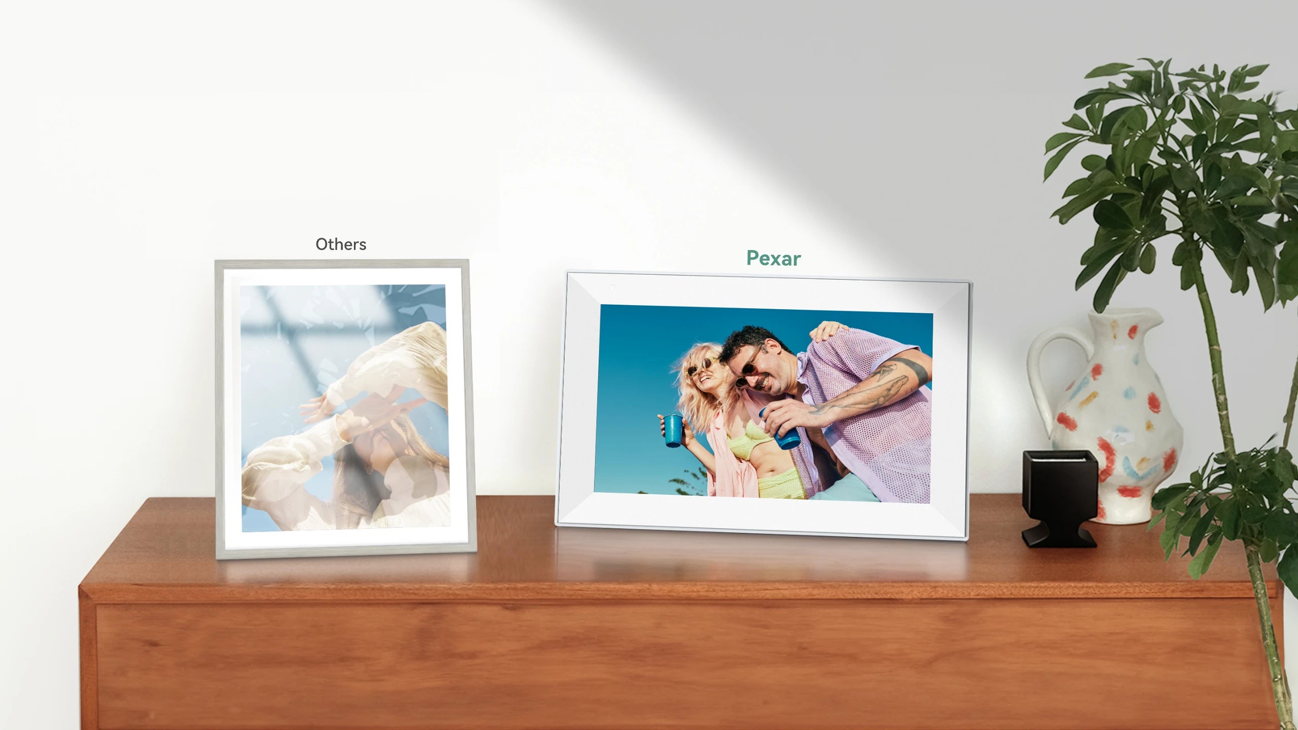 Digital photo frame displaying a couple on a wooden surface with a plant in the background, compares pexar and other frames on anti-glare feature