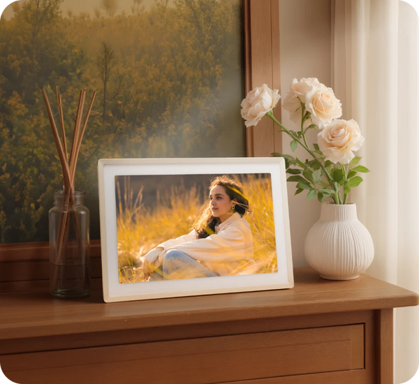 Framed photo of a woman in nature on a wooden surface with flowers and decor.