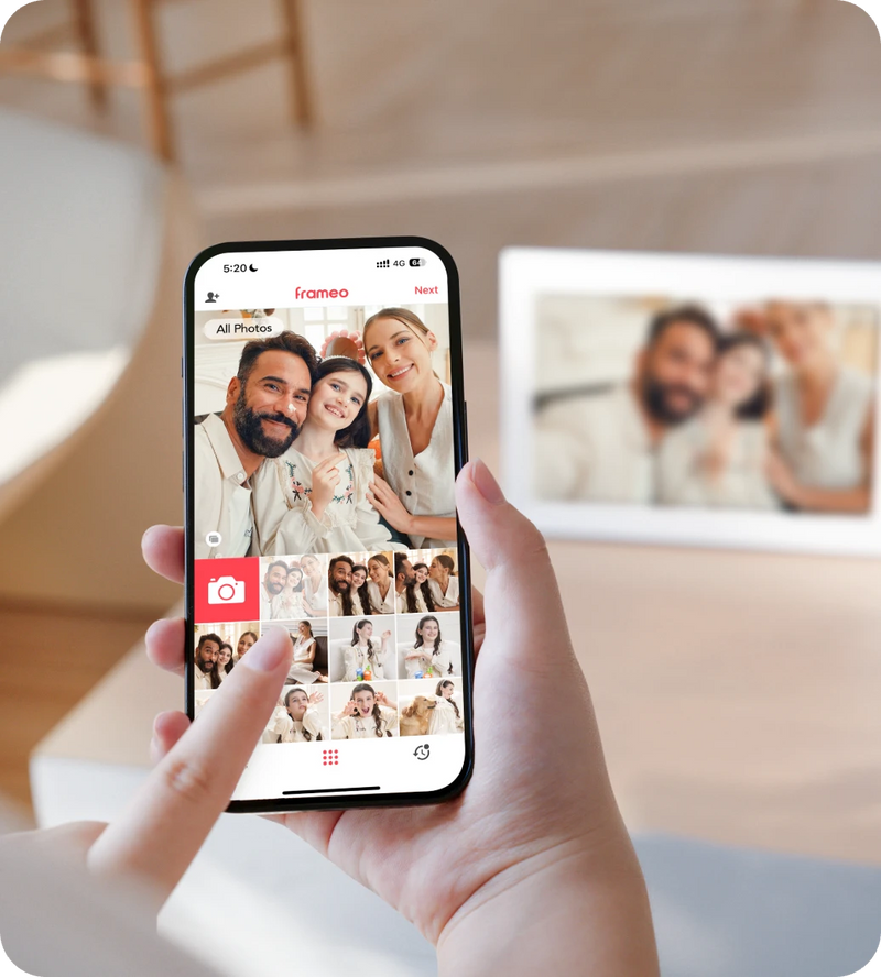Person using a smartphone app to select photos, with a framed photo in the background.