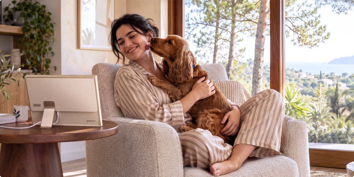 Woman cuddling her dog in an armchair beside a Champagne Gold Pexar digital photo frame