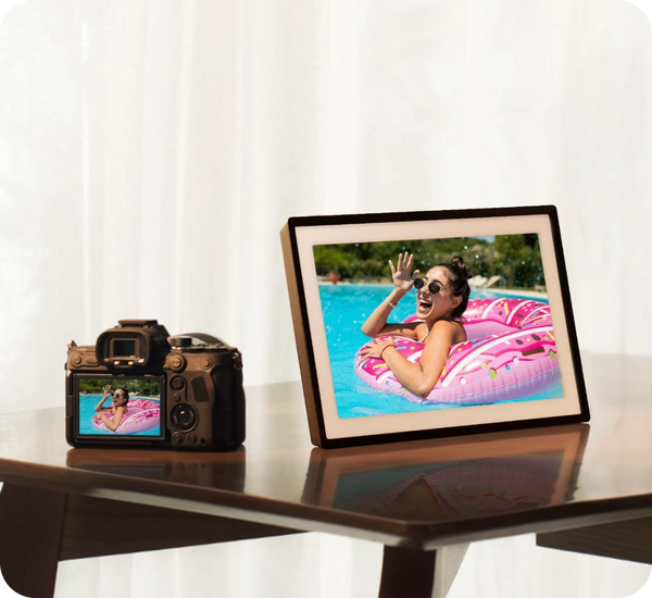 Digital photo frame displaying a woman on an inflatable ring by a pool, next to a camera.