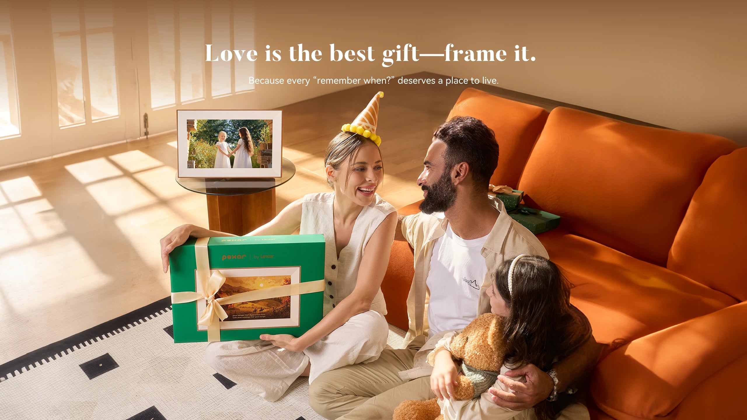 Family in a living room, mom is holding a gift which is pexar digital picture frame and displaying the picture of two girls